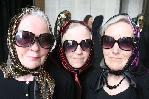 A close up of three participants wearing silk headscarves and dark sunglasses