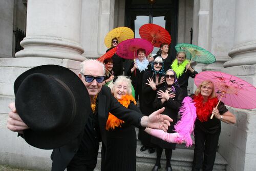 Participants outside City Hall posing with colourful parasols and feathers