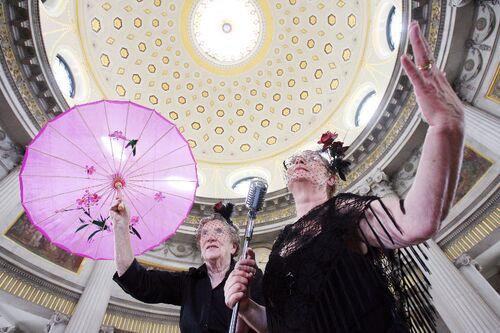 Two participants seen from below posing with a parasol and a microphone