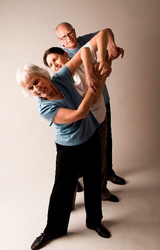 Three participants posing in a line in movement with arms bent towards the ceiling