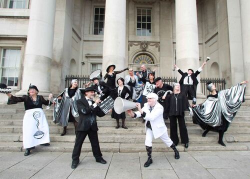 An ensemble of participants in full costumes scattered across a large stone set of steps