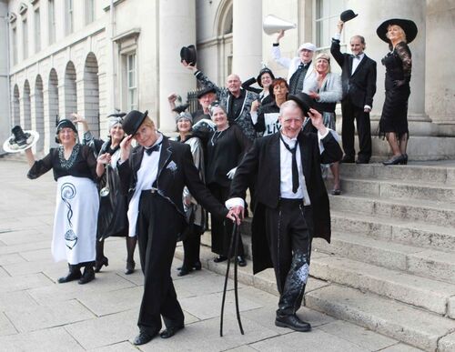 An ensemble of participants in costume spread along the steps of a large stone building
