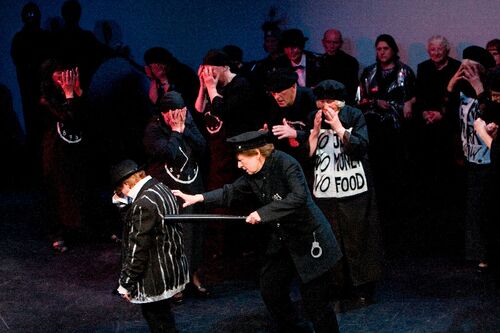 An ensemble of participants dressed in black on stage