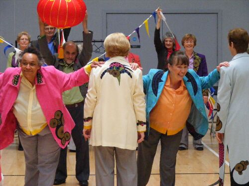 Participants in movement with others holding colourful bunting and a lantern in the background