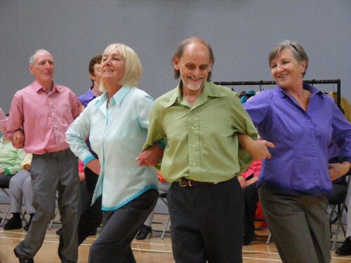 Three participants in movement with their arms linked together
