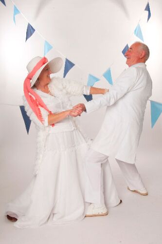 Two participants dancing together holding hands with blue bunting behind them
