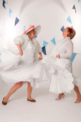 Two participants all in white in movement with blue bunting behind them