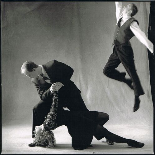 Two figures in movement together and a third mid-jump in a photo studio in black and white