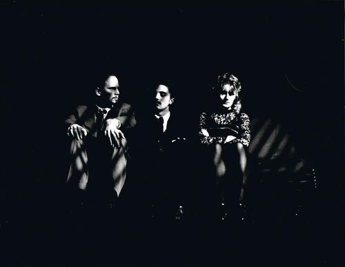 Three figures seated on a sofa side by side