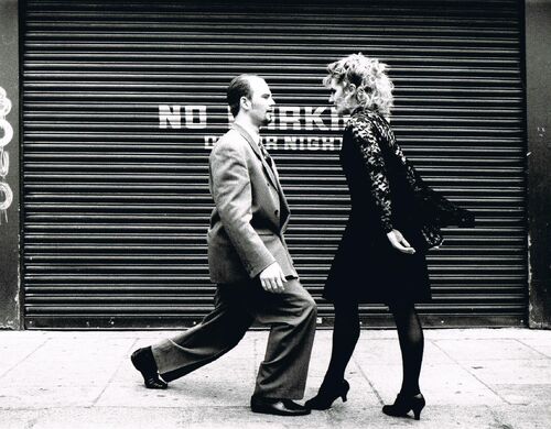 Two figures in movement facing each other on a street