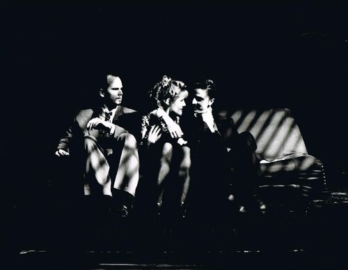 Three figures seated side by side on a sofa