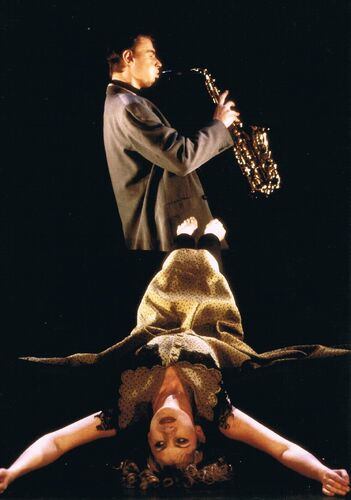 One figure lying back with arms outstretched and a saxophonist in side profile behind them