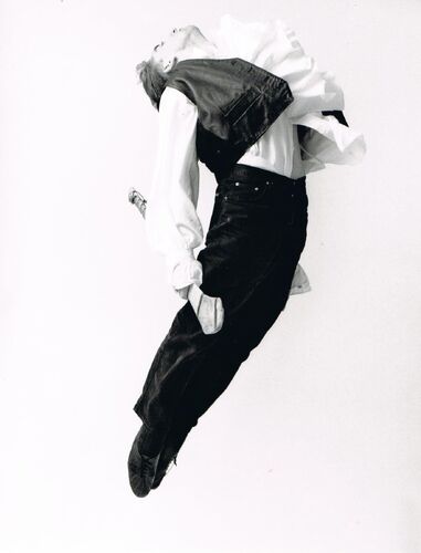 A figure airborne mid-jump with head thrown back and a hurl in his hand