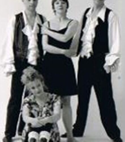 Three figures standing and one sitting for the camera in a white studio space in black and white