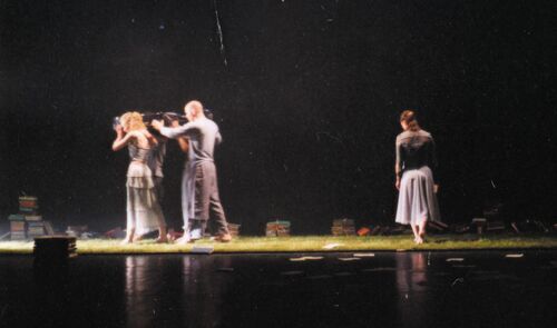 Four figures gathered together on stage with one lone figure in movement on the right