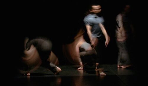 Four figures on a dark stage blurred in motion