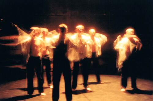 An ensemble of dancers in movement, blurred in motion