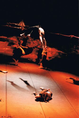 Figures blurred in motion on stage with one figure suspended above and one in movement on the floor