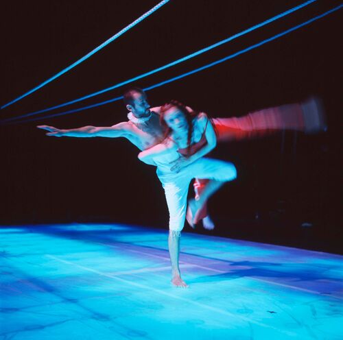 Two figures in movement cast in blue light