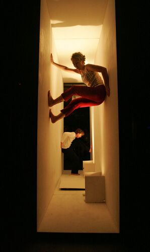 Two figures in movement in a narrow rectangular space