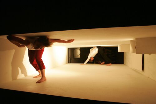 Two dancers in movement in a narrow rectangular set