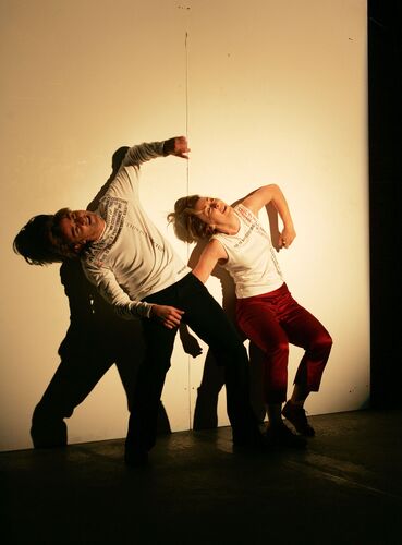 Two figures in movement against a blank white wall