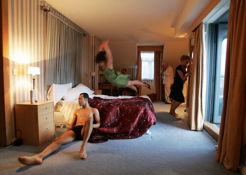 Figures scattered throughout a hotel room with one airborne over the bed