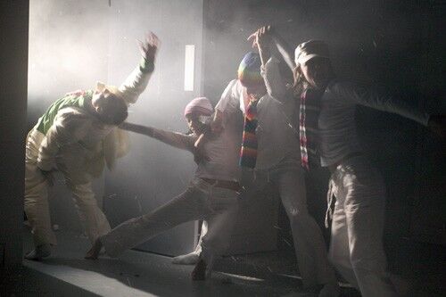 Four figures in movement on a haze filled stage