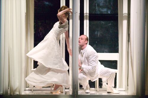 Two cubicles open on one side each with a figure dressed in white in movement inside