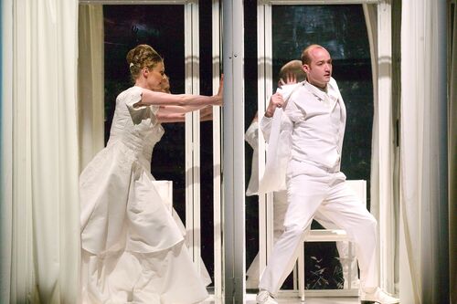 Two cubicles with one side open each with a figure dressed in all white inside in movement