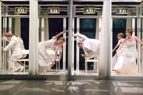 A line of four cubicles with EXIT signs above them each with a figure inside in movement