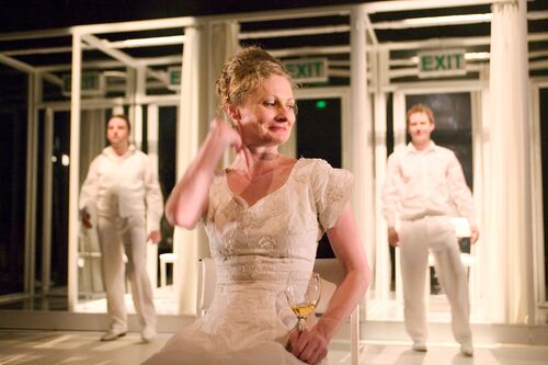 Two figures in the background either side of another figure to the front holding a wine glass