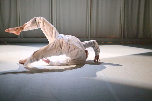 A figure dressed all in white in movement on the floor