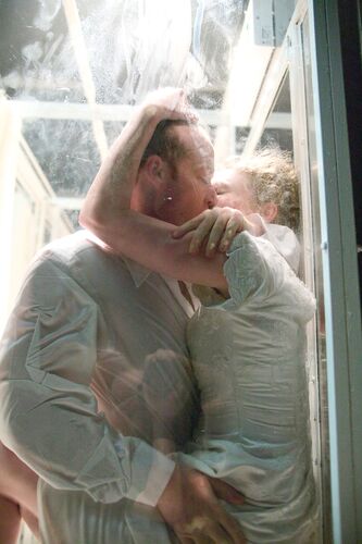 Two figures in an embrace kissing seen through a transparent screen
