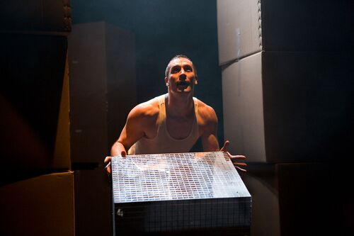 A figure holding the edge of a large reflective box