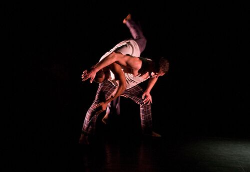 Two figures in movement with one mid-lift over the other's back