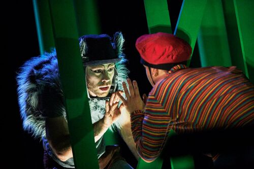 Ivonne Kalter & Mateusz-Szczerek facing each other through a stage set of trees