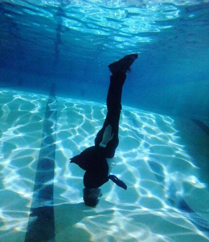 David Bolger upside-down underwater with his head resting on the pool floor