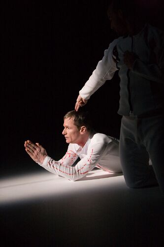 A figure with palms pressed together lying on the stage floor