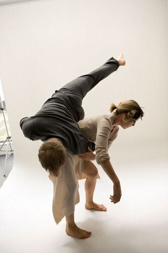 Two figures in movement with one mid-lift over the other's back