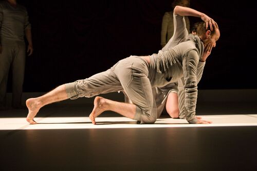 Two figures in movement on the floor with one clasping the other's head