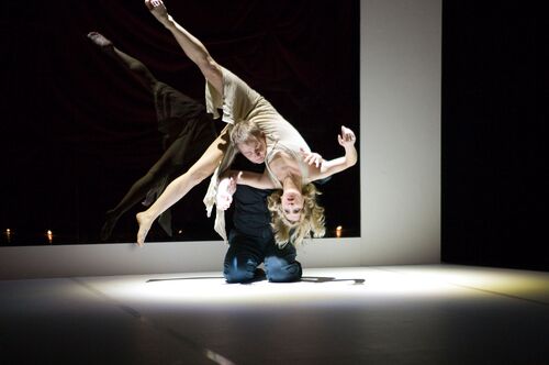 Two figures in movement with one lifting the other while kneeling