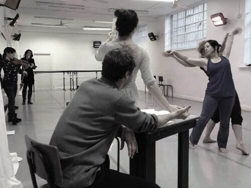 Musicians, two figures in movement and a figure standing by a table in a dance studio