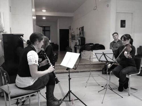 Three musicians playing in a studio space in black and white