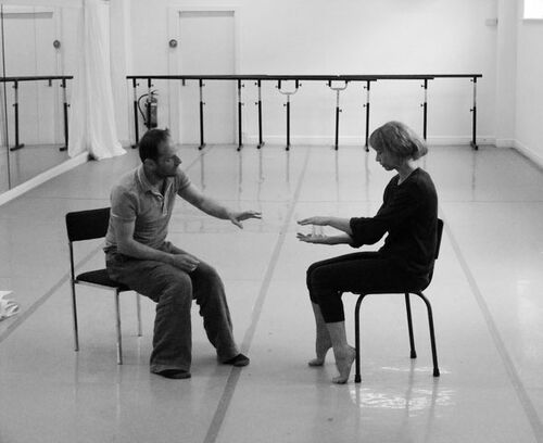 Two figures sitting opposite each other in a studio