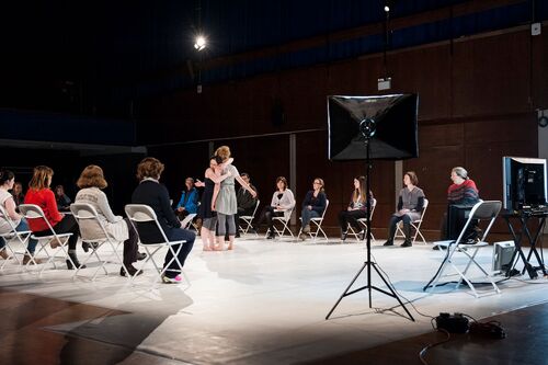 Two dancers in an embrace with audience seated on 3 sides
