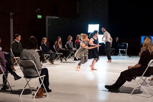 Three dancers in movement with audience seated on 3 sides