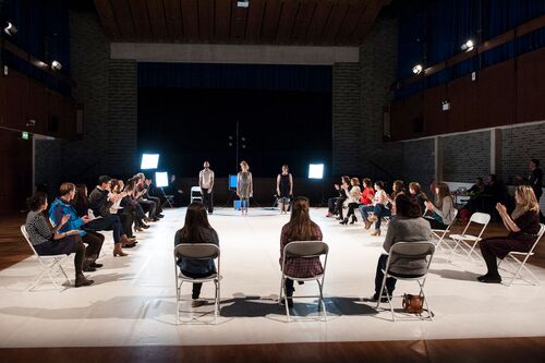 Three dancers standing in space with audience on 3 sides