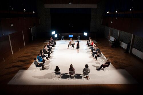 Three dancers in movement, seen from above, with audience on 3 sides