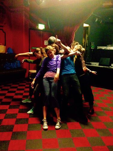 An ensemble of participants in motion close together on a checkered floor